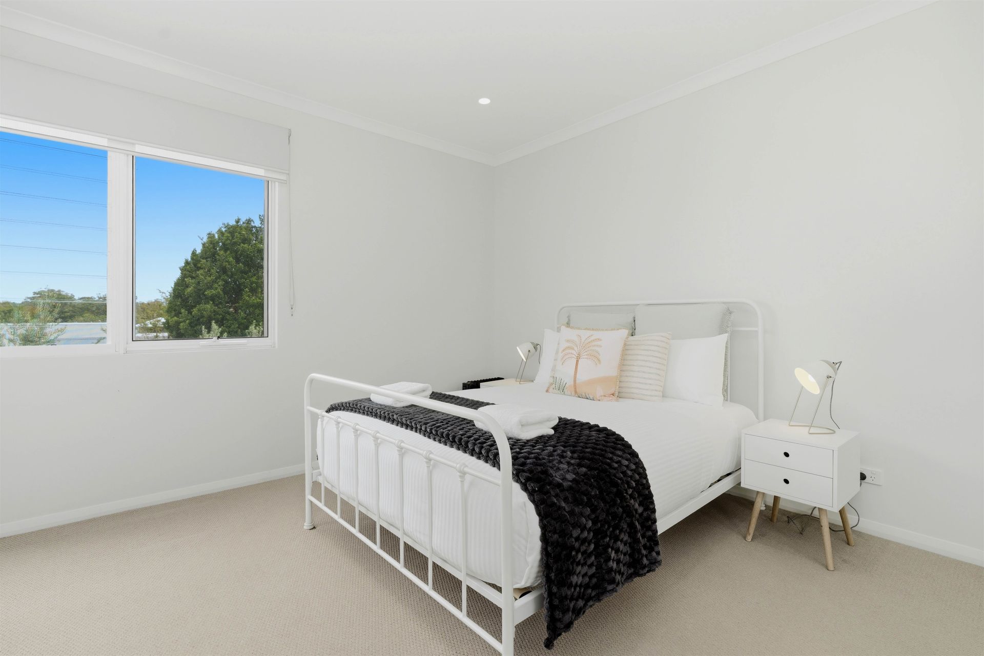 Queen bedroom with white iron bed frame and garden outlook