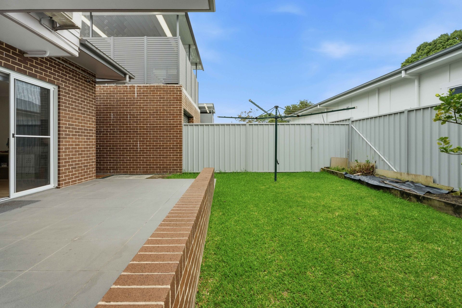 Fenced grassy courtyard beside the house with room for kids to play